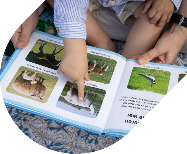 Een kind en een volwassenen kijken samen in een boekje met plaatjes