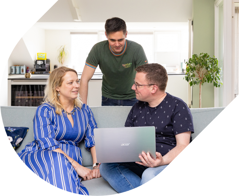 Draagmoeder en vader op de bank met een computer en daarachter een tweede vader