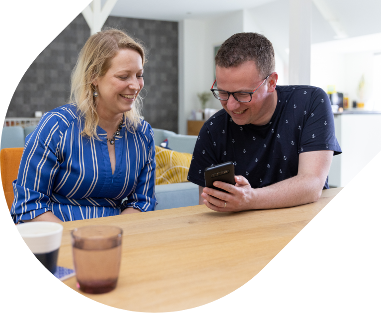Eiceldonor en draagmoeder kijken samen naar een telefoonscherm en lachen.